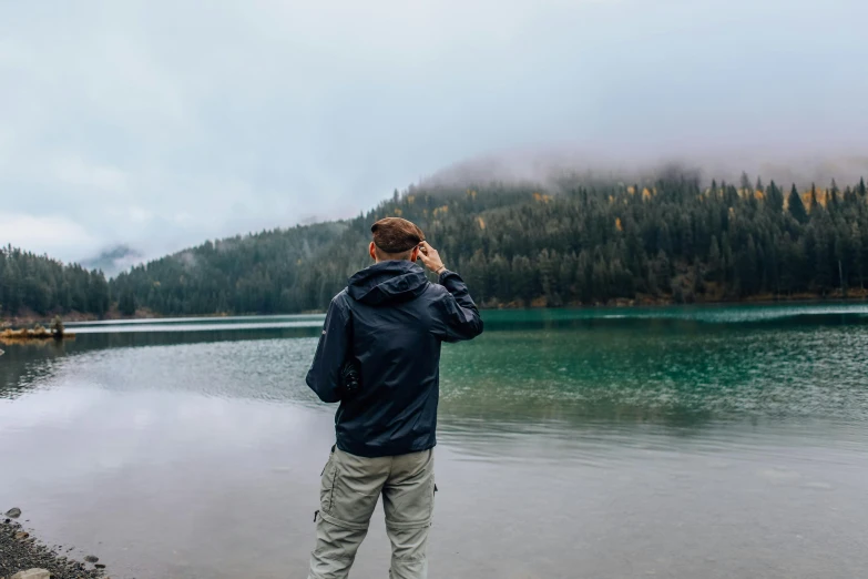 a man is standing by the water talking on a phone