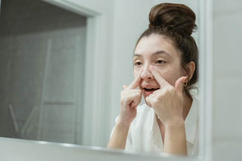 an asian woman looks in the mirror as she brushes her eyes