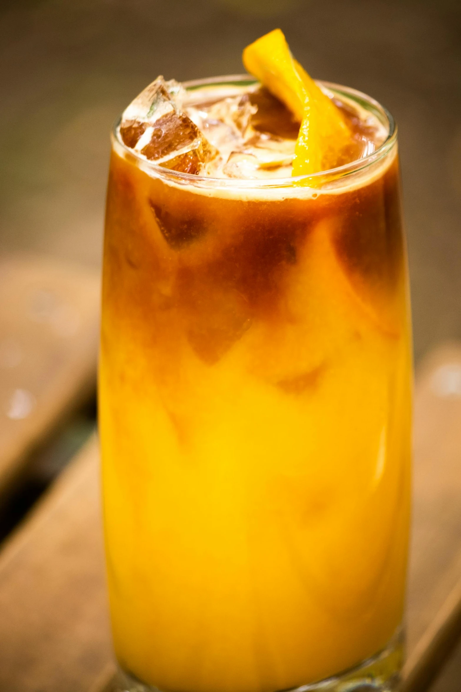 a glass with orange juice and ice on a wooden table