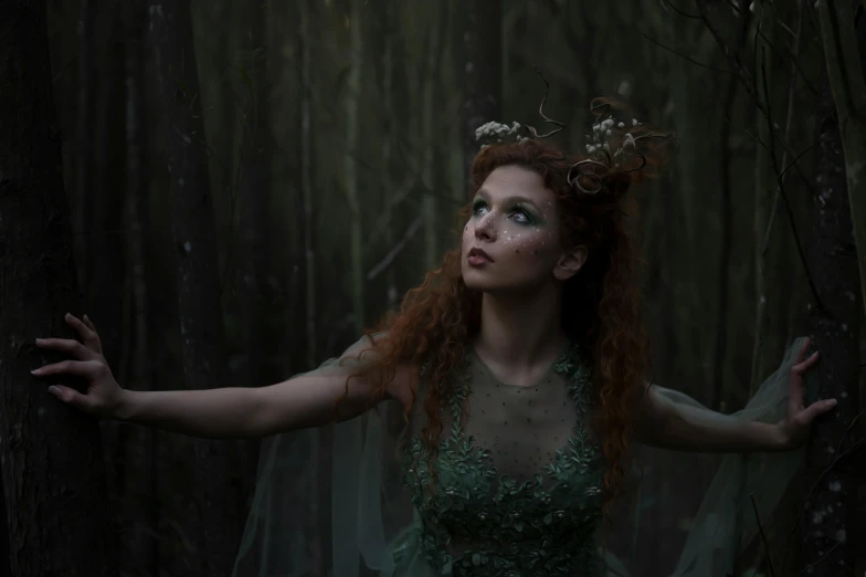 a woman with red hair and make up stands in a dark forest