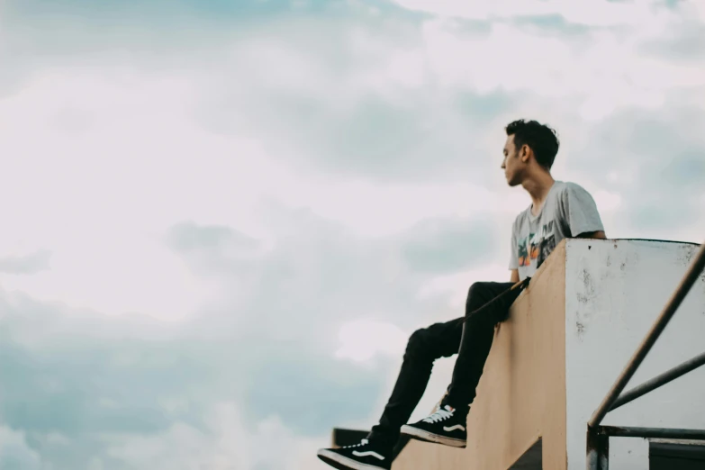 a man sitting on top of a wooden post