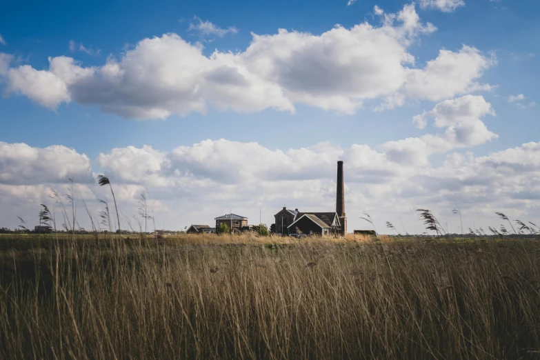 a house with a smoke stack standing in the middle of an open field