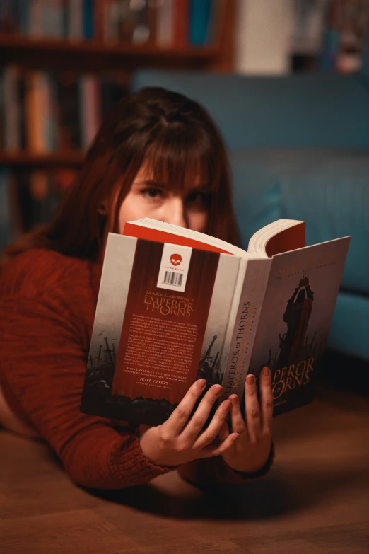 a girl laying down on the floor reading a book