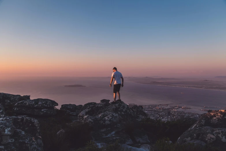 the man standing at the top of a mountain on his phone