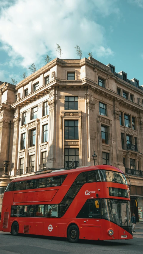 a red double decker bus drives through the city