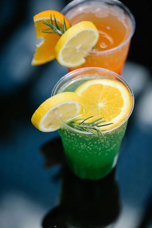 three orange and lime beverages are arranged in cups