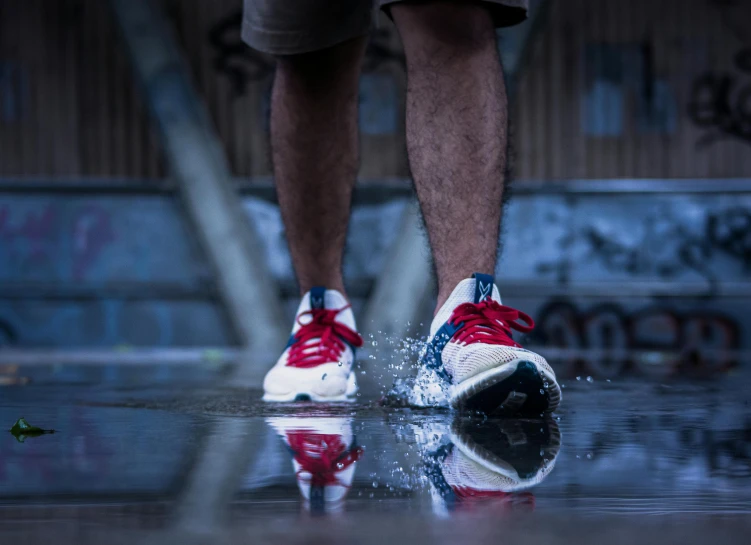 a man's foot and shoes is reflecting on a wet surface