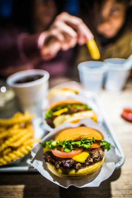 a person sitting at a table with several hamburgers and french fries