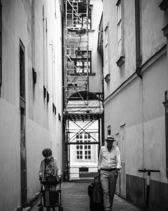 a man walking down a street next to a woman with luggage