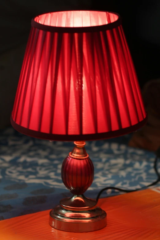 a red lamp on a table with a blue carpet in the background