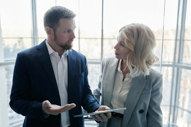 two business people in an office environment standing and talking