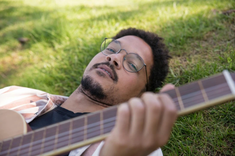 a man laying on the grass with an acoustic guitar