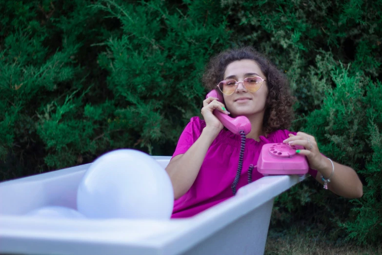 a lady sitting in a bathtub talking on the telephone