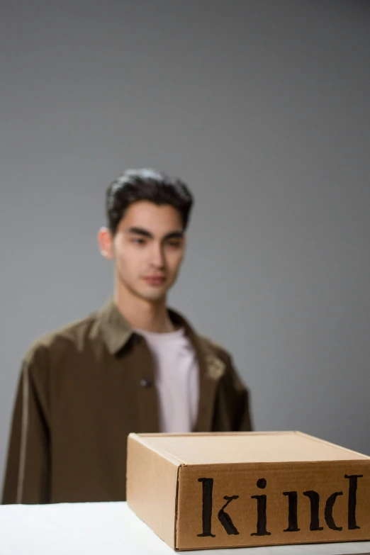 a man standing next to a cardboard box with kind on it