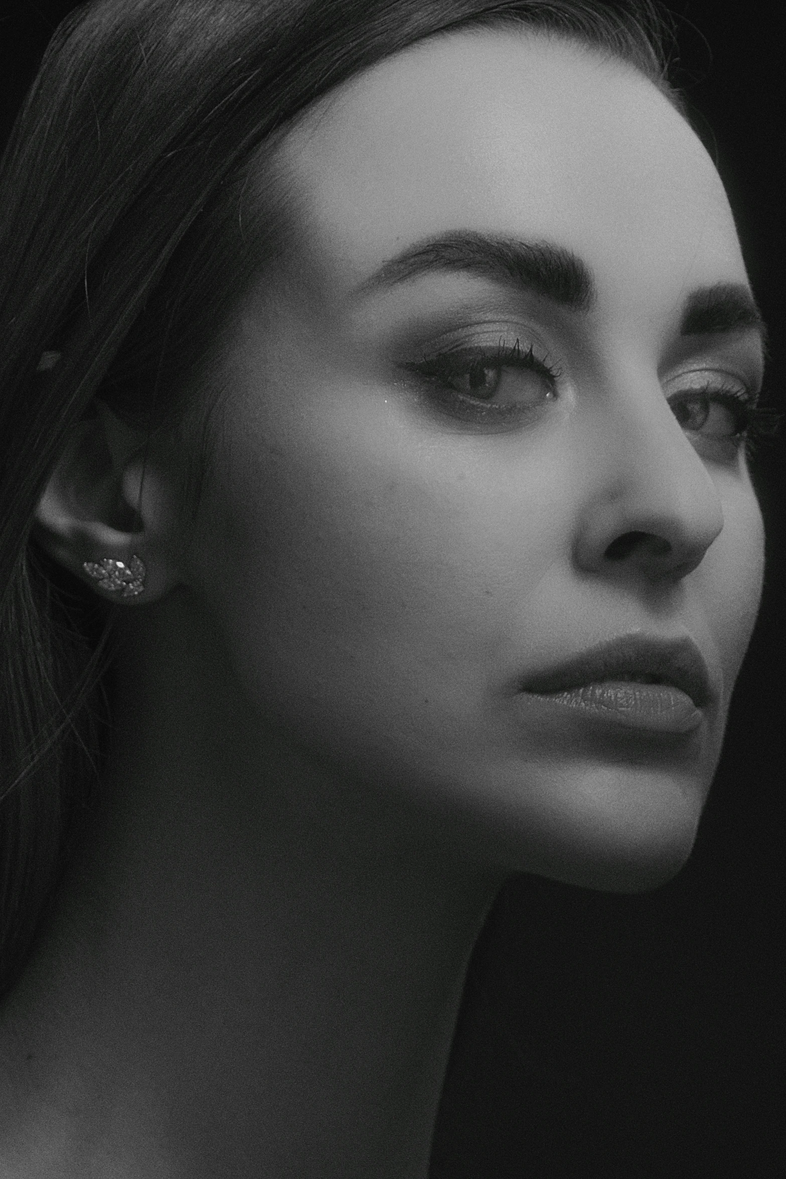 black and white image of a woman's face with ear studs