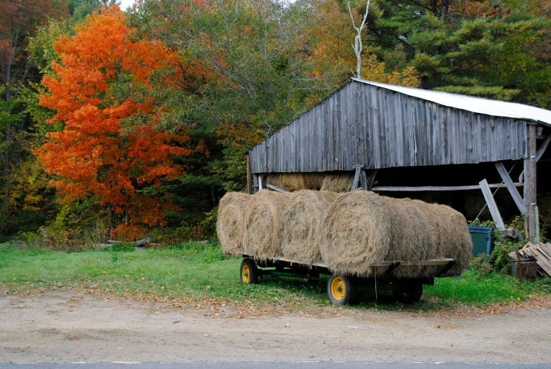 a wooden barn sitting next to a hay truck