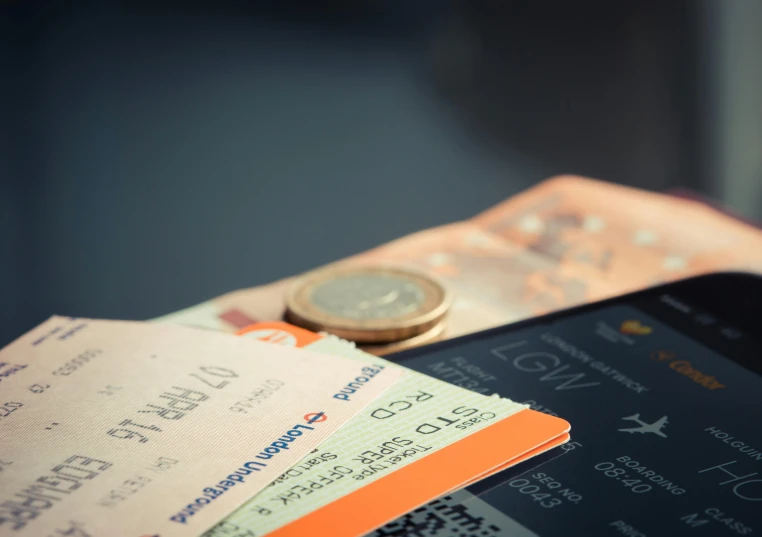 a smart phone with two boarding tickets and a money