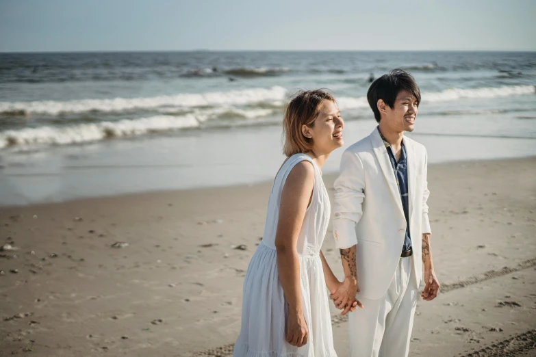 a man and woman standing on top of a beach