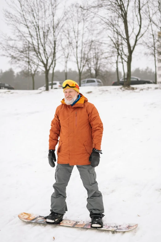 a smiling man in a brown parka on a snowboard