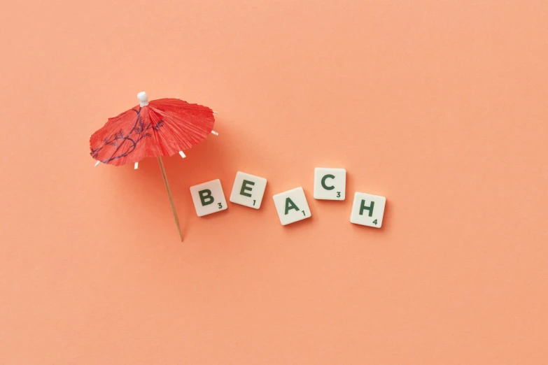 an umbrella sitting next to the letters beach written on tiles