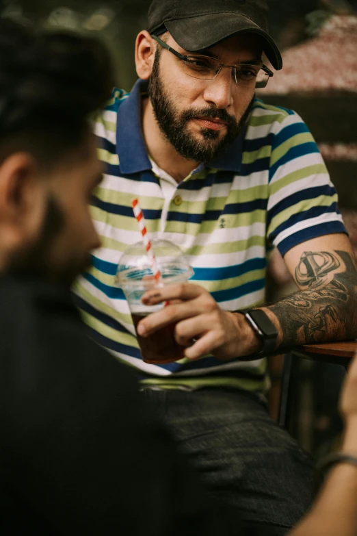 a man with a tattoo holding up a drink
