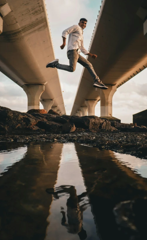 the man is running in the water by the bridge