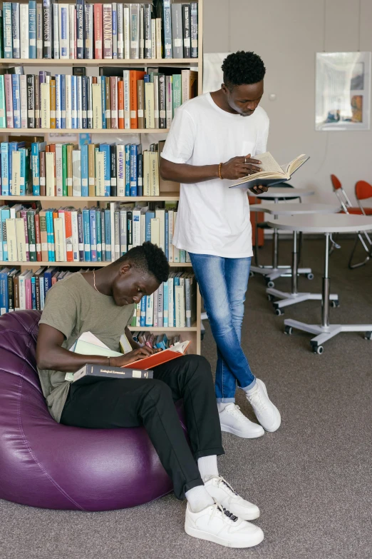 two men reading together in the liry