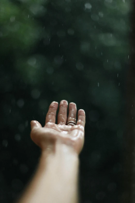 someone's hand in the rain with their fingers up