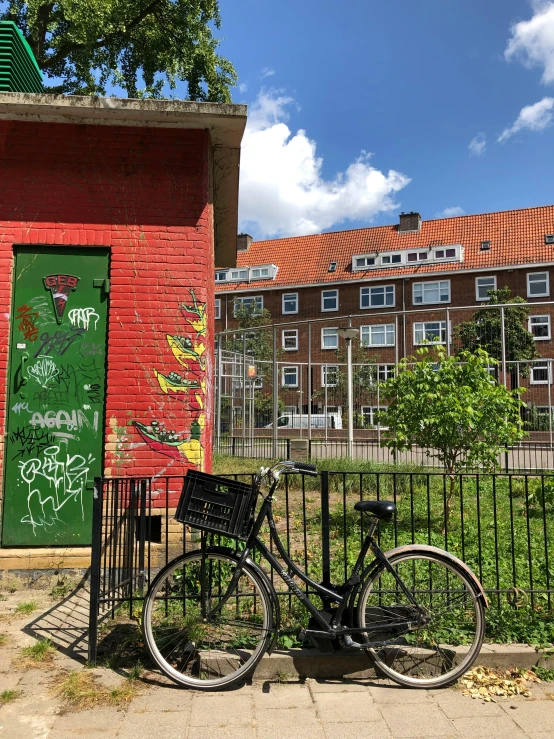 a bicycle parked next to a gate with graffiti on it