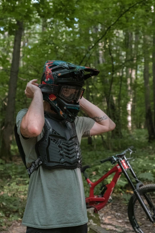 a person stands in a forest next to a bicycle