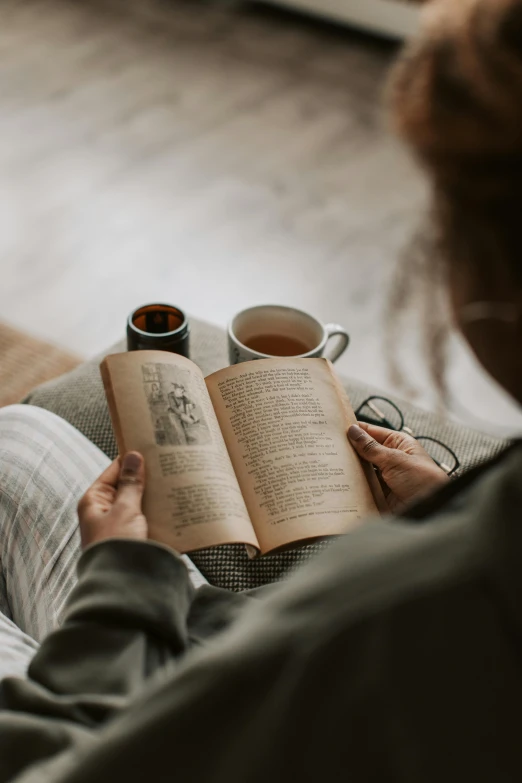 woman reading and drinking from a cup of coffee