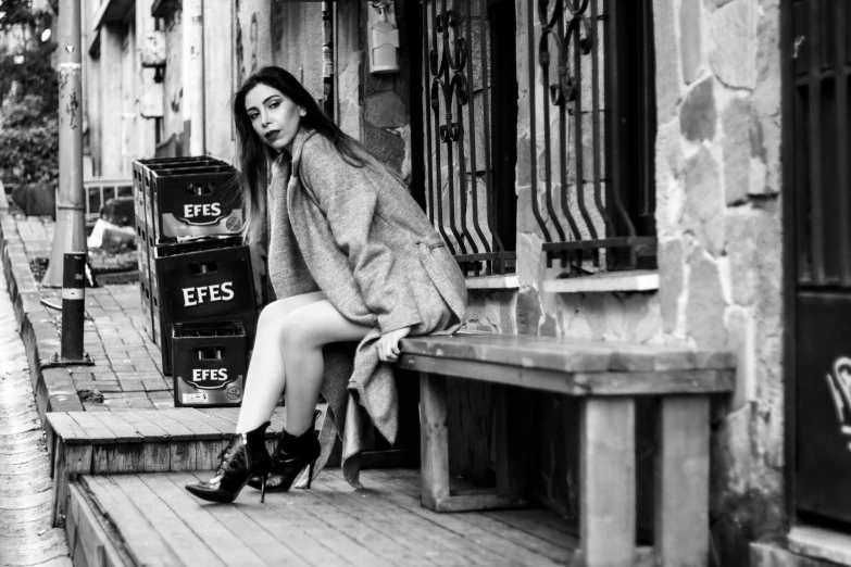 a woman with long hair sits on steps near a bench