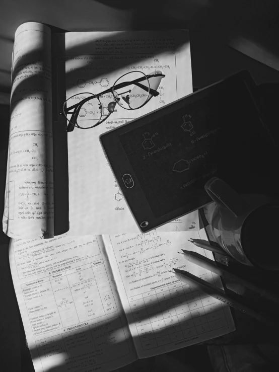 some books, pens and paper with a po of some glasses