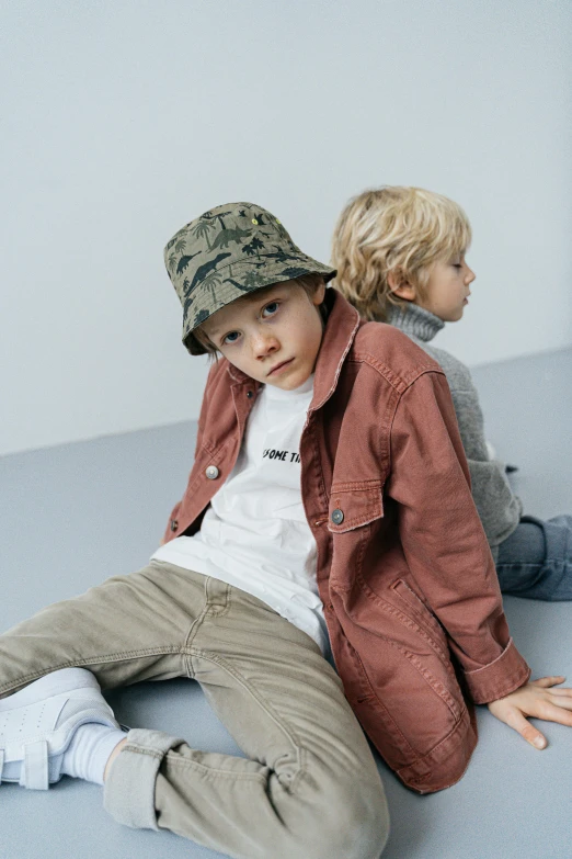 two young children wearing caps are sitting on the floor