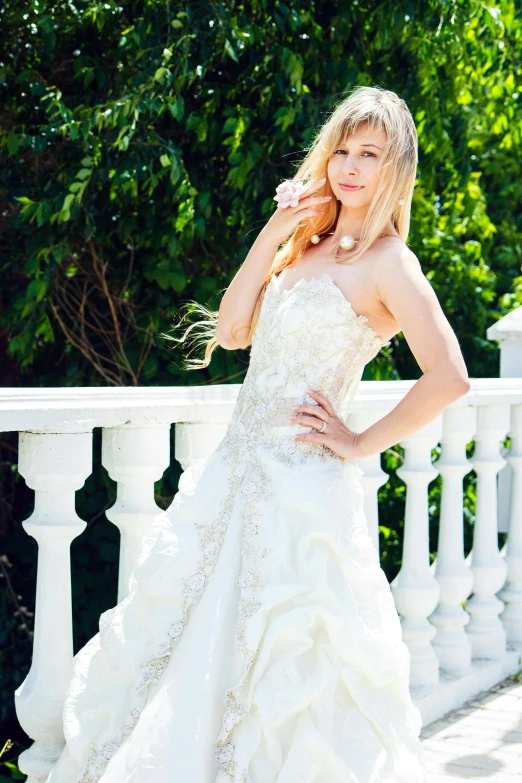 a young lady poses on the side of a bridge in a wedding dress