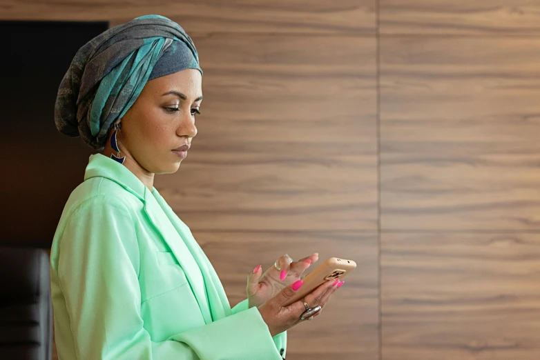 a woman is wearing a turban while holding a cell phone