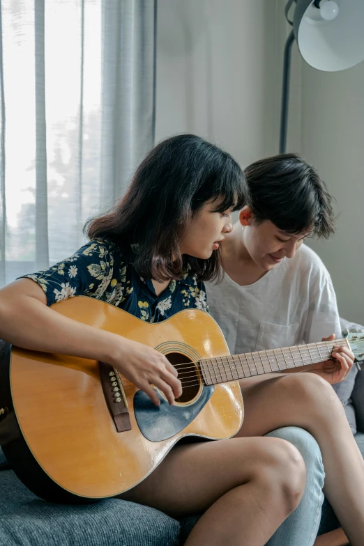 two people are looking at an acoustic guitar