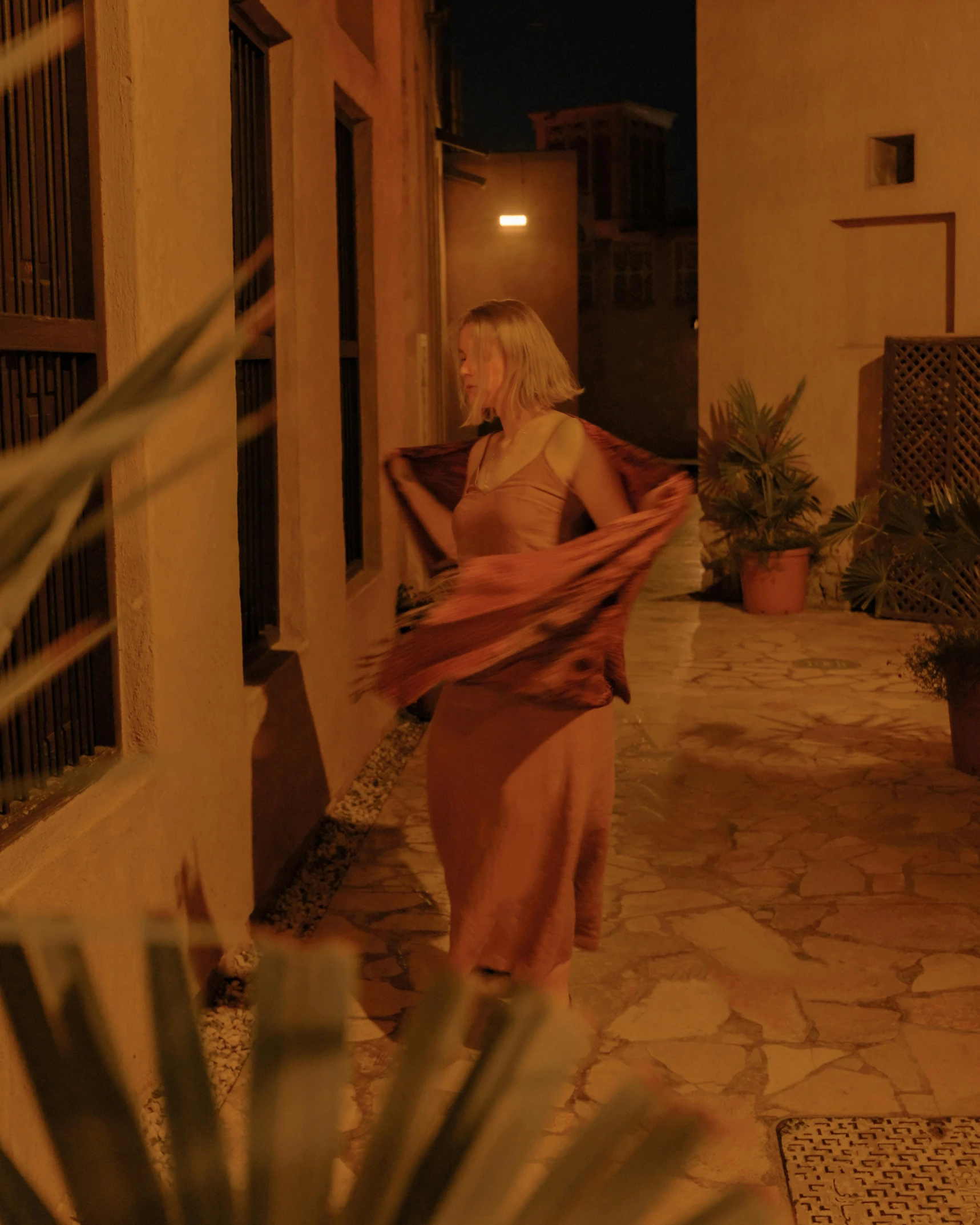 the woman is wearing a tan gown and holding a shawl