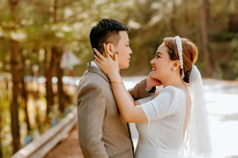 wedding po of the bride and groom hugging in front of trees