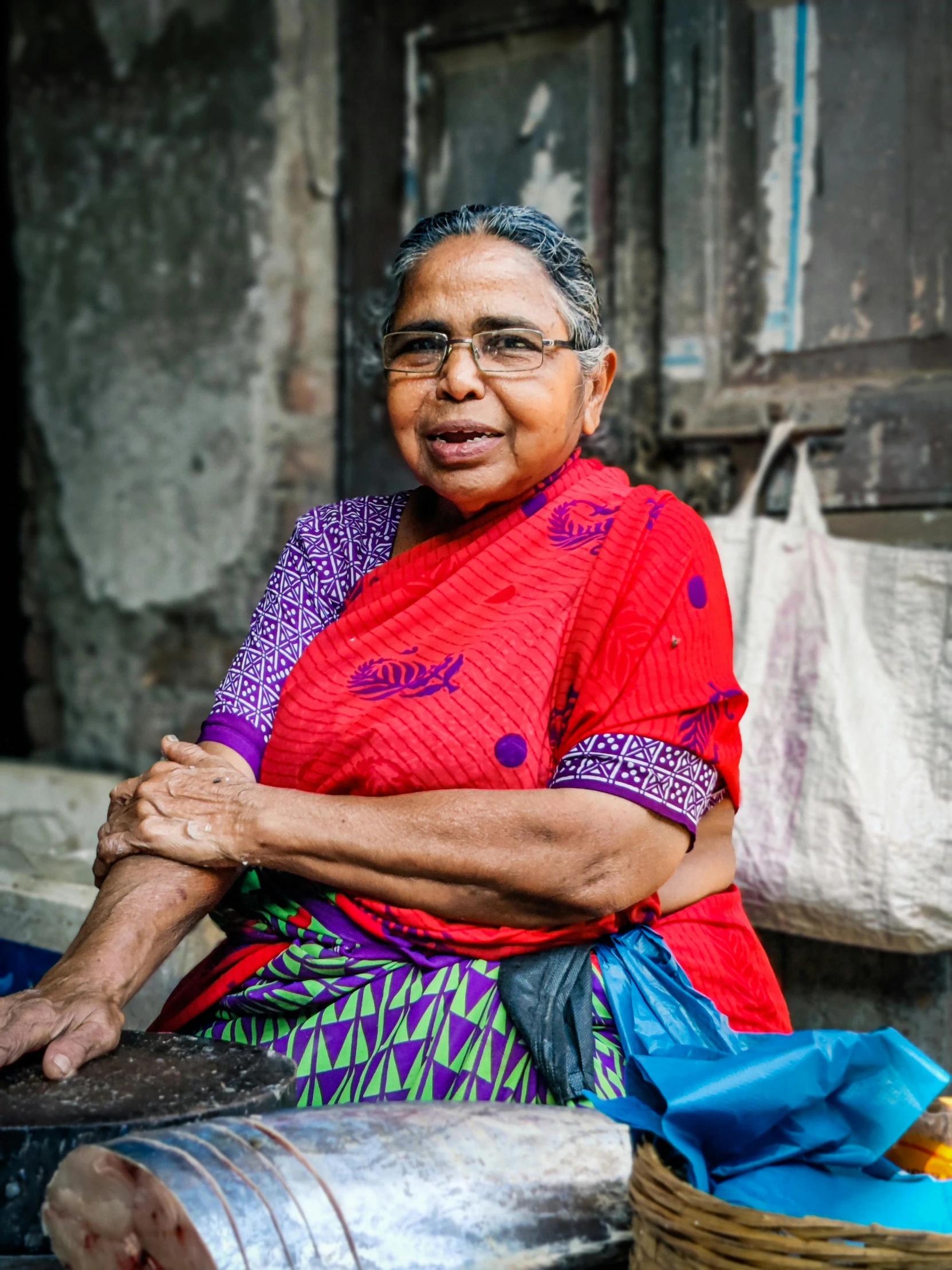 an elderly woman sitting on the ground near a basket