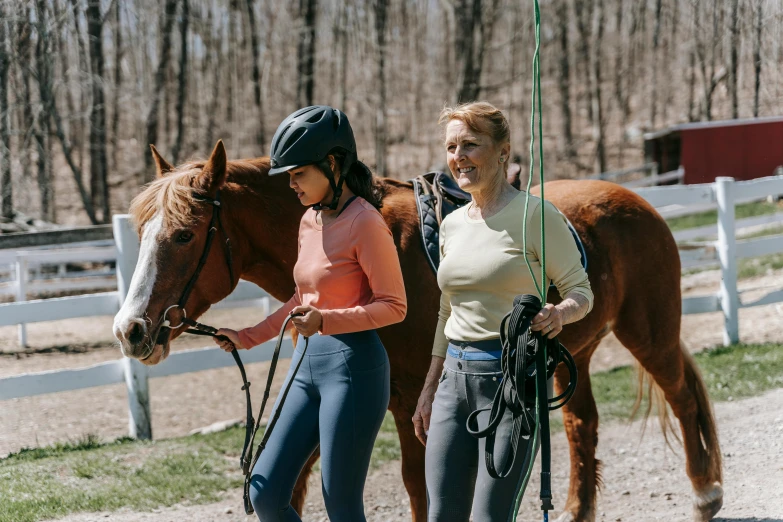 an older woman leading a younger lady with her horse