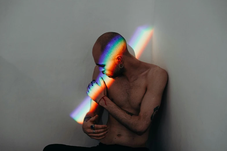 a man wearing black pants is posing for a po with a rainbow light