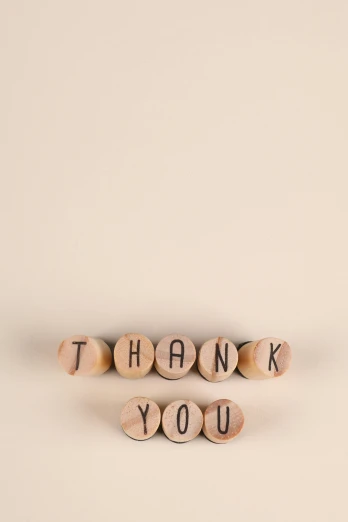 a cork spelling thank you with two pairs of wine corks on the left side
