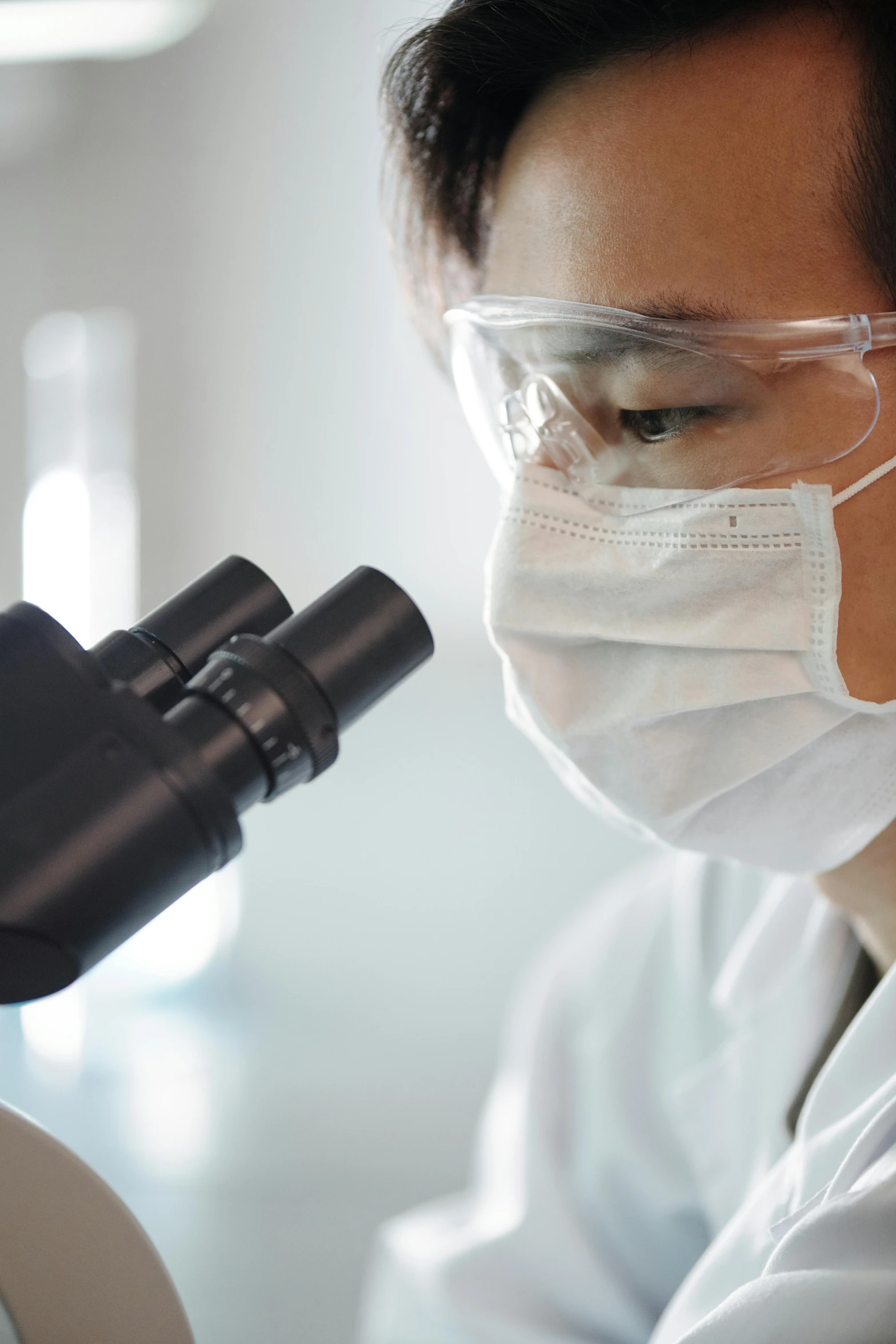 a person in a lab coat looking at a microscope