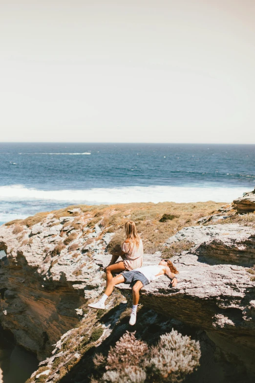 there is a woman sitting on the edge of a cliff