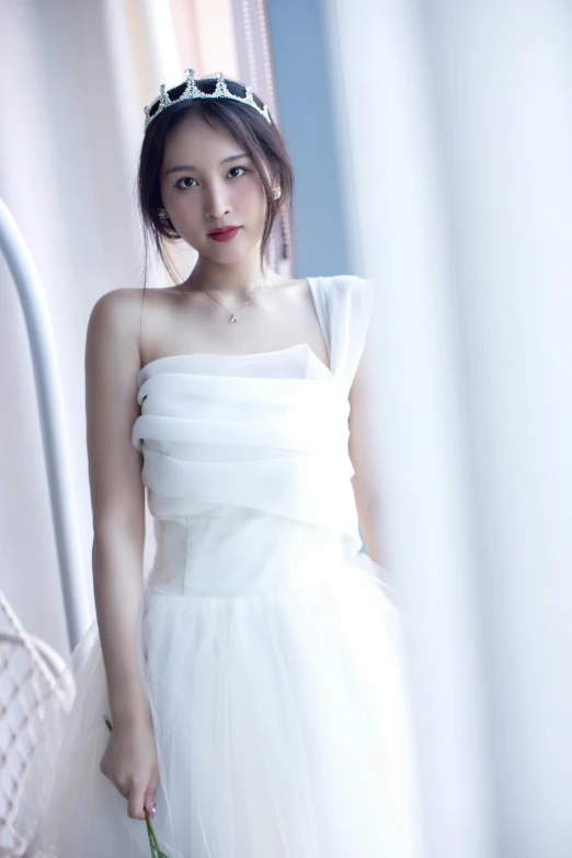 a young woman in a white dress standing with her eyes closed