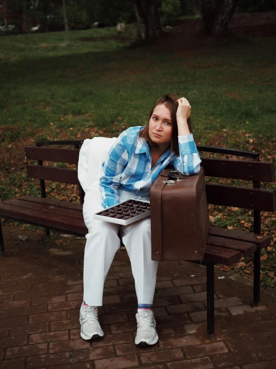 a woman sitting on a bench, holding a briefcase and her hands behind her back