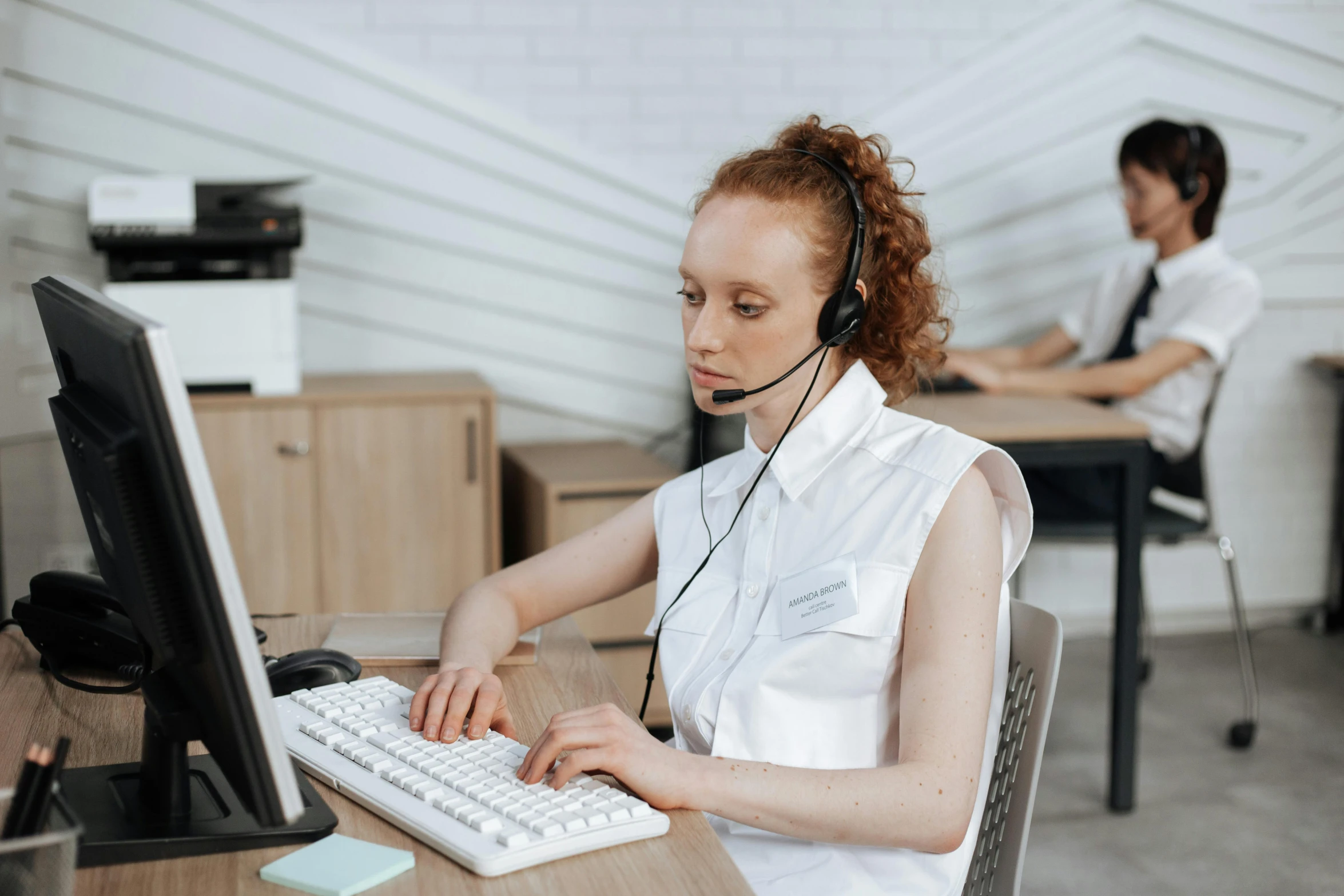 a woman sitting in front of a computer wearing a headset