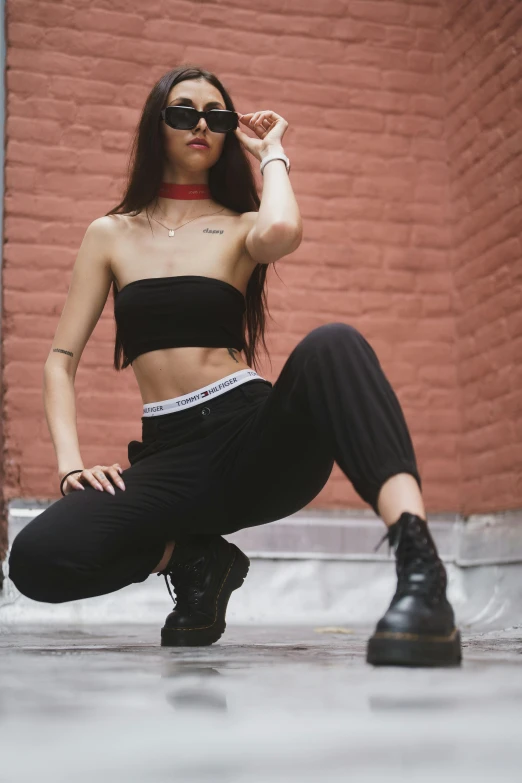 a woman posing on the ground in a crop top and black pants