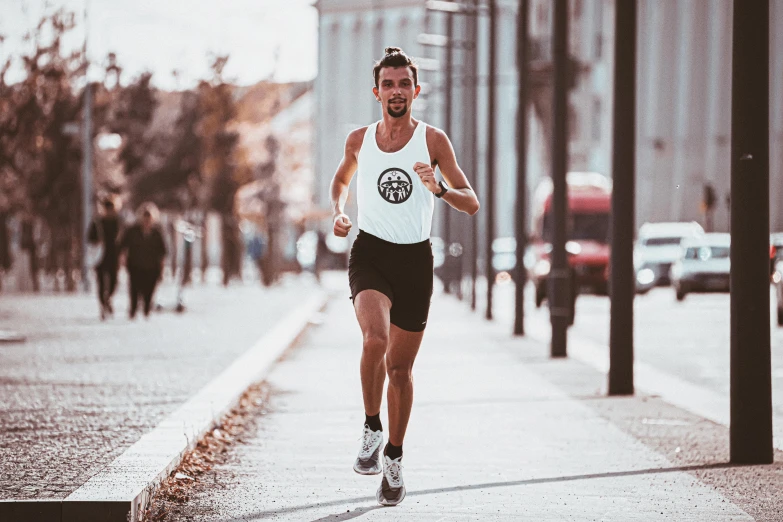 a man running along a wet road wearing a white tank top